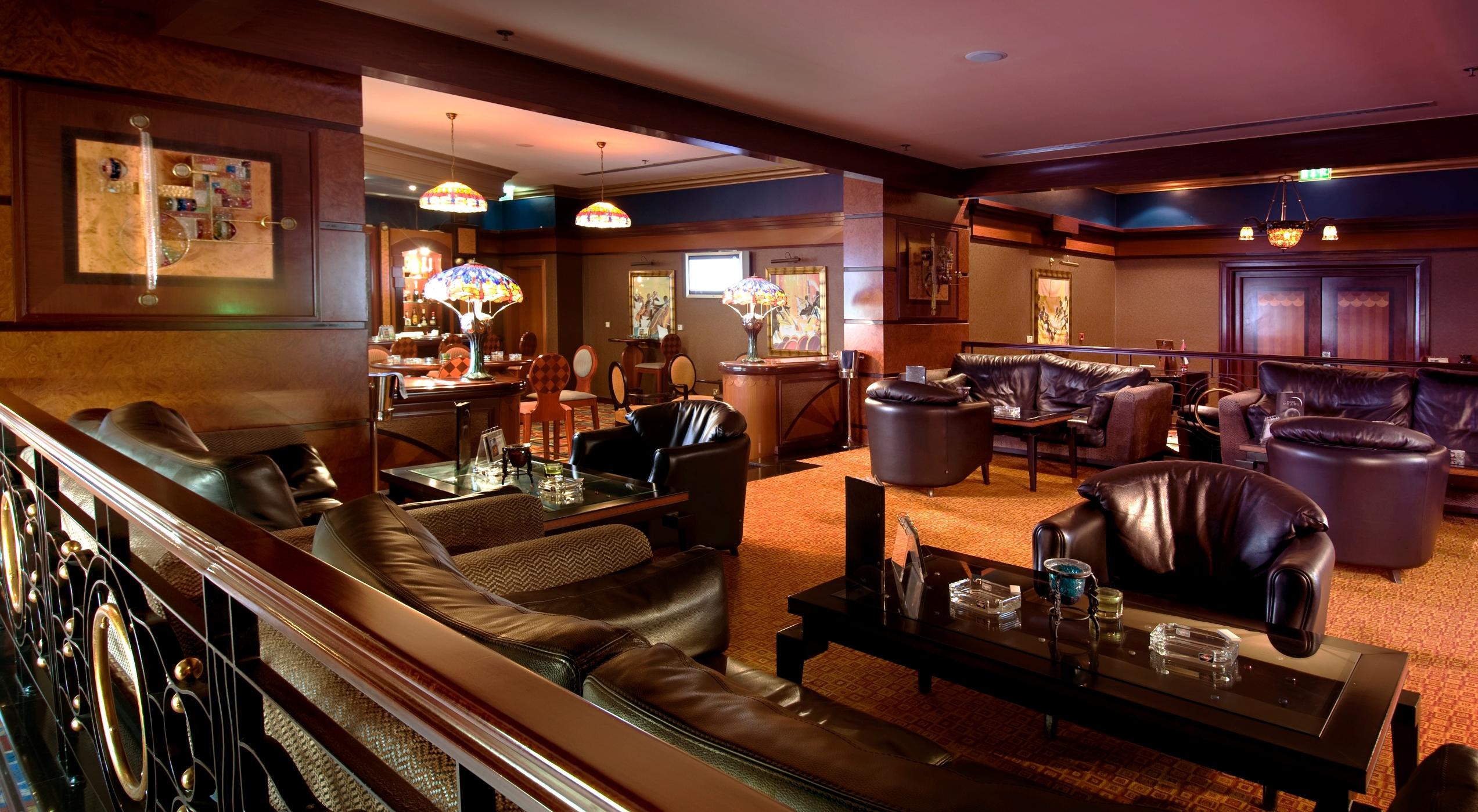 Al Raha Beach Resort & Spa Абу Даби Интериор снимка The photo depicts a stylish lounge area featuring comfortable seating and an inviting atmosphere. There are several plush leather armchairs and sofas arranged around low tables. The space is well-lit, with stained glass lamps providing warm light. Th