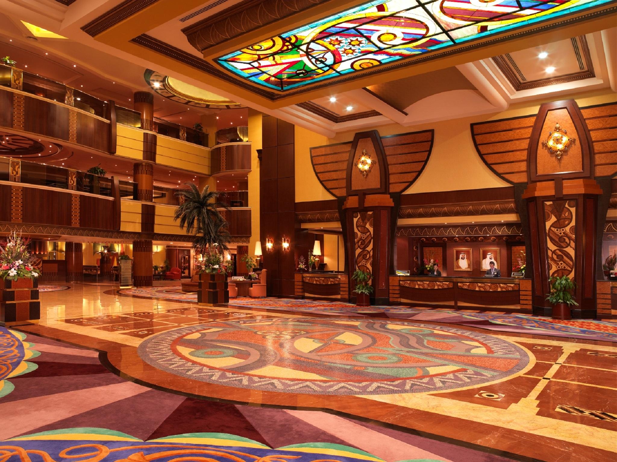 Al Raha Beach Resort & Spa Абу Даби Интериор снимка The photo depicts an elegantly designed hotel lobby. It features a grand ceiling with intricate stained glass and decorative patterns. The floor is adorned with colorful, ornate designs, including circular patterns. The lobby is spacious, with wooden