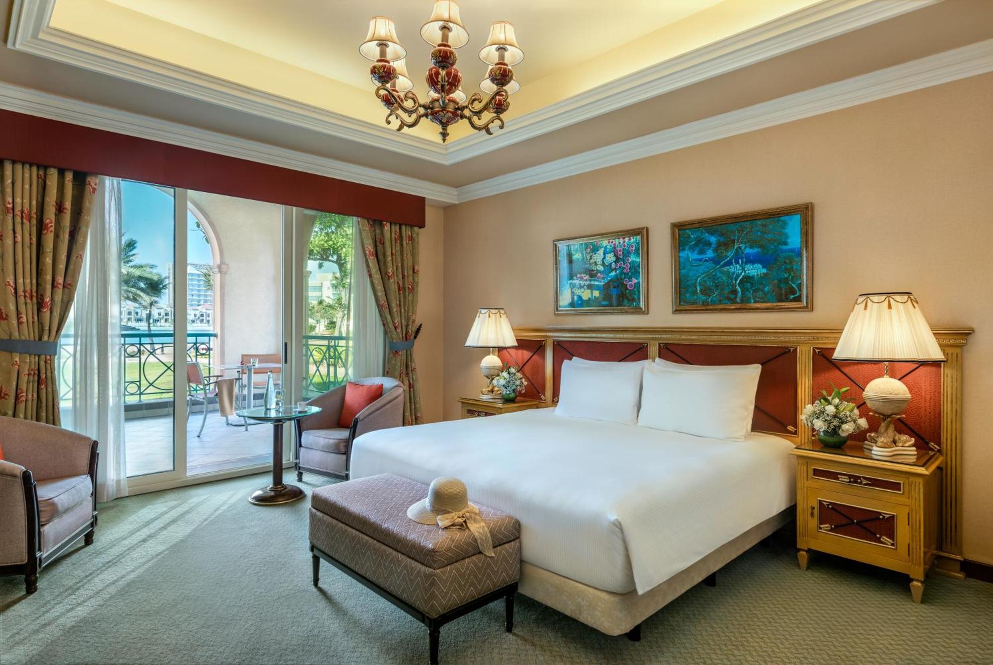 Al Raha Beach Resort & Spa Абу Даби Екстериор снимка The image depicts a well-furnished hotel room. It features a large bed with white linens, flanked by two bedside lamps. Above the bed, there are two pieces of artwork hanging on the walls. To the side, there is a comfortable armchair and a small tabl
