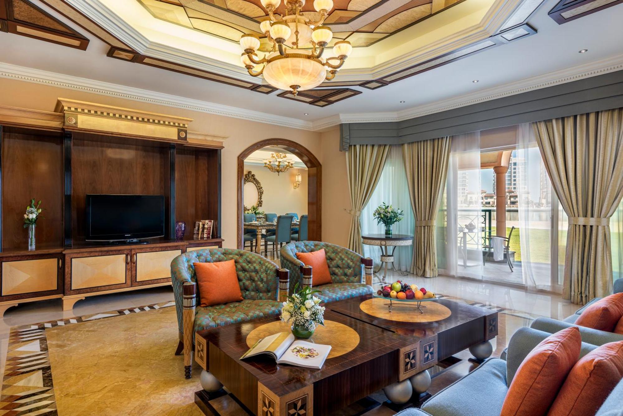 Al Raha Beach Resort & Spa Абу Даби Екстериор снимка The photo depicts a luxurious living room with elegant decor. It features two green upholstered sofas accented with orange pillows, arranged around a stylish coffee table. The coffee table showcases decorative items, including a magazine and a bowl o