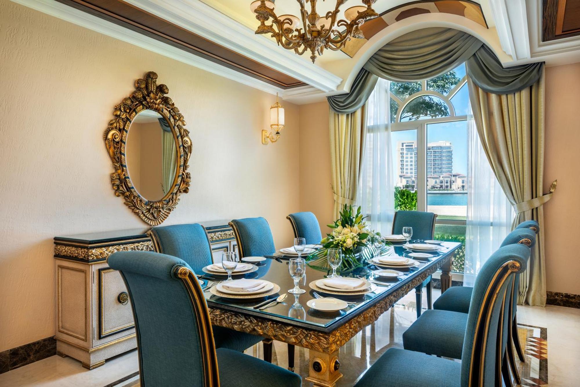 Al Raha Beach Resort & Spa Абу Даби Екстериор снимка The photo features an elegantly decorated dining room. It includes a long, polished table set for a meal with plates, glasses, and decorative items, surrounded by plush blue chairs. The room is adorned with sophisticated details, such as an ornate mi