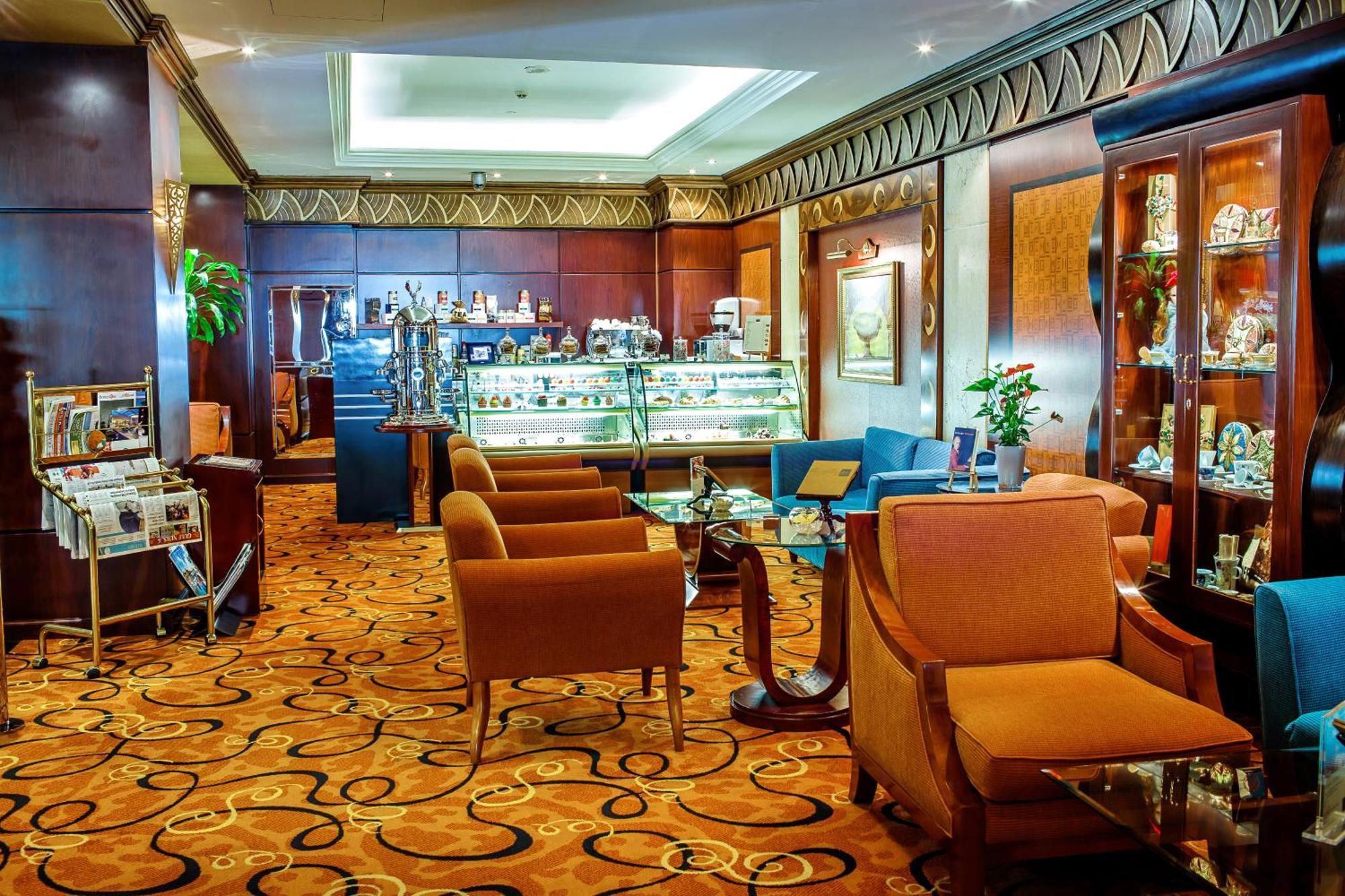 Al Raha Beach Resort & Spa Абу Даби Екстериор снимка The photo shows a cozy and elegantly designed lounge or café area. It features plush seating with brown armchairs and a blue couch. In the background, there is a display case filled with various items, likely including pastries or decorative goods. T