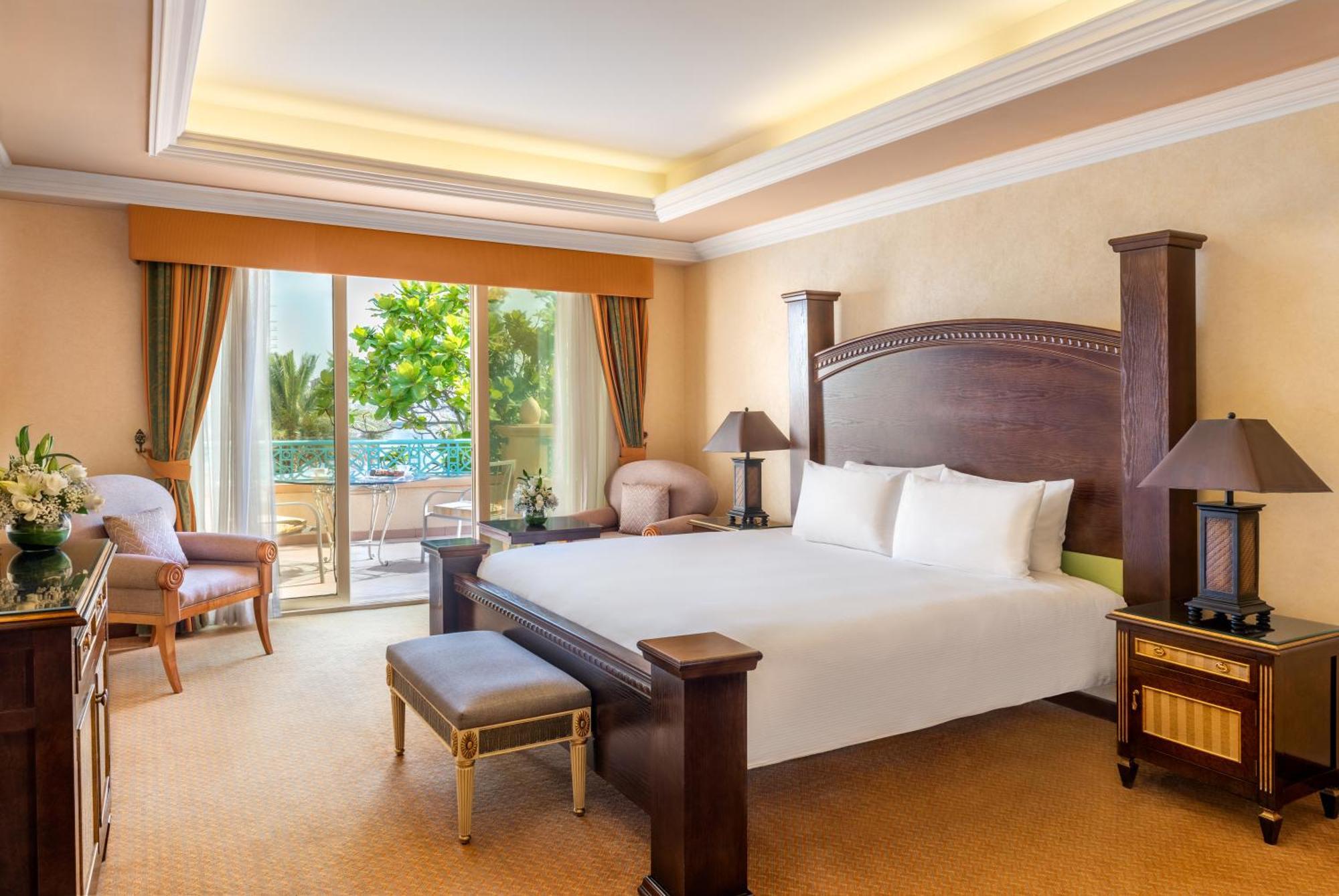 Al Raha Beach Resort & Spa Абу Даби Екстериор снимка The photo shows a well-appointed hotel bedroom. It features a large bed with white bedding, flanked by bedside tables with lamps. The room has light-colored walls and a warm-toned carpet. There is a comfortable seating area with a chair and a small t