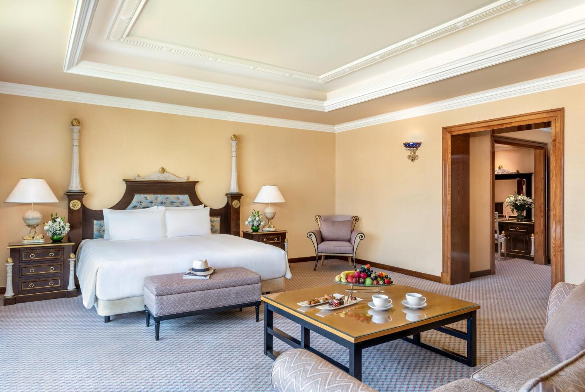 Al Raha Beach Resort & Spa Абу Даби Екстериор снимка The photo shows an elegant hotel room, featuring a large bed with white linens, flanked by stylish bedside tables and lamps. The room has a warm color palette, with light brown walls and a plush carpet. A comfortable armchair is positioned nearby, an